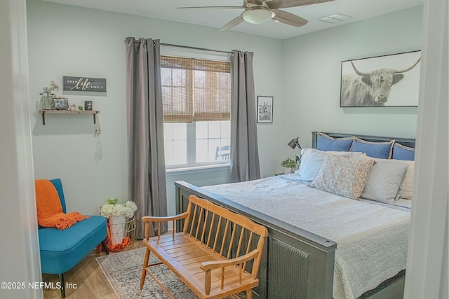 bedroom with ceiling fan, wood finished floors, and visible vents