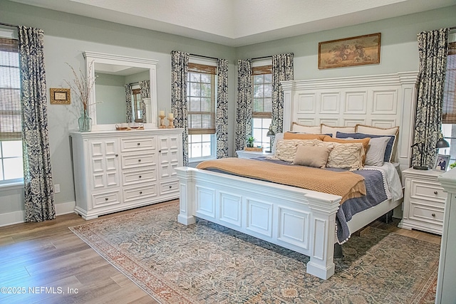 bedroom featuring light wood-style flooring, baseboards, and multiple windows