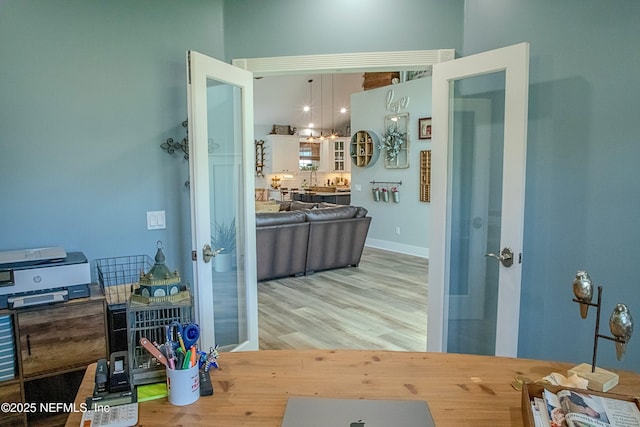 hallway featuring wood finished floors, baseboards, a notable chandelier, and french doors