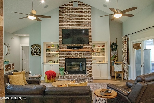 living area featuring high vaulted ceiling, a ceiling fan, wood finished floors, and a fireplace