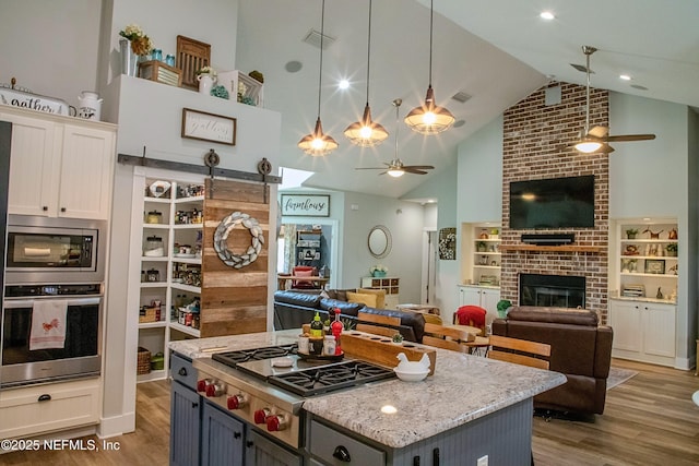 kitchen featuring a ceiling fan, open floor plan, stainless steel appliances, and visible vents