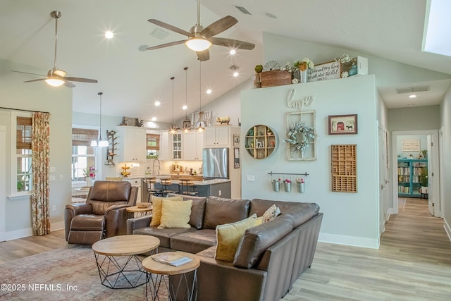 living room with light wood-type flooring, visible vents, high vaulted ceiling, and ceiling fan