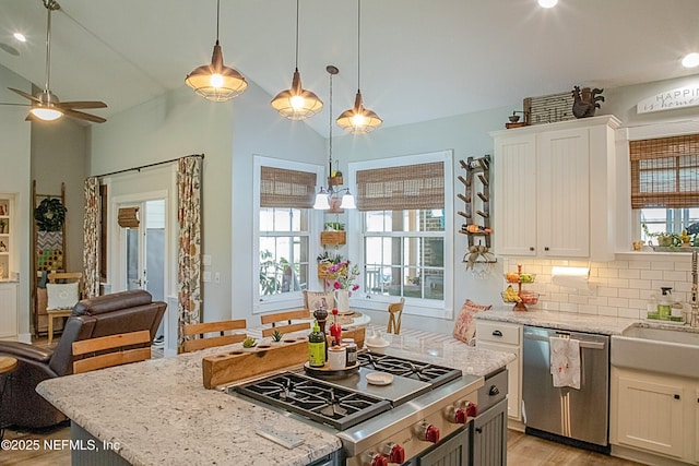 kitchen with white cabinets, stainless steel appliances, a kitchen island, open floor plan, and ceiling fan