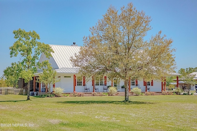 view of front facade with a standing seam roof, covered porch, a front yard, and metal roof