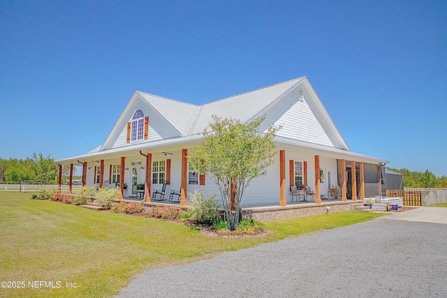 view of front of property with fence, a front yard, metal roof, and covered porch