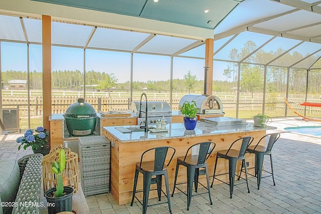 view of patio with outdoor wet bar, area for grilling, and fence