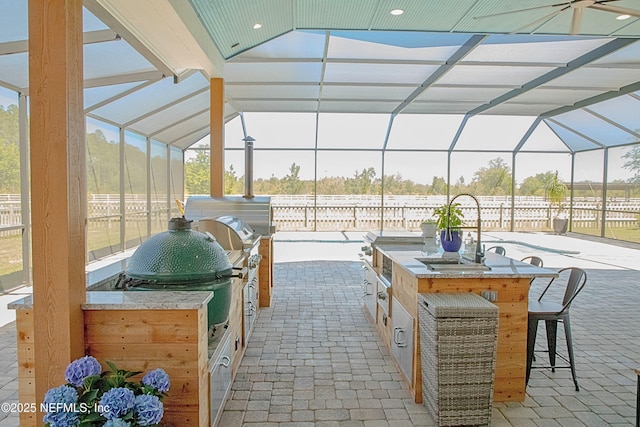 view of patio / terrace with exterior kitchen, outdoor dry bar, a lanai, and a sink