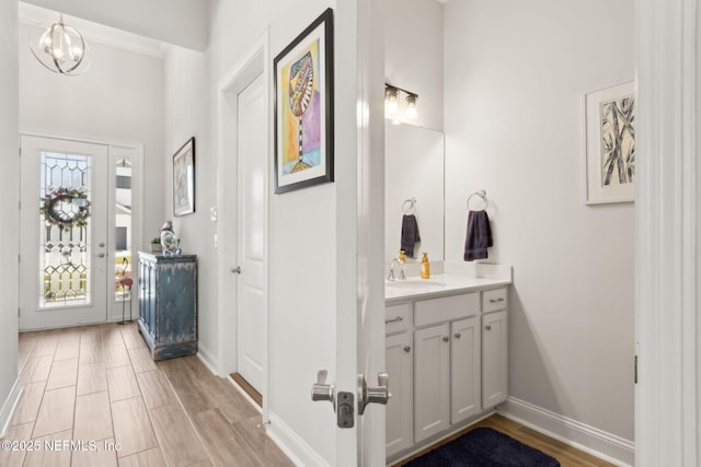 bathroom with baseboards, an inviting chandelier, wood finished floors, and vanity
