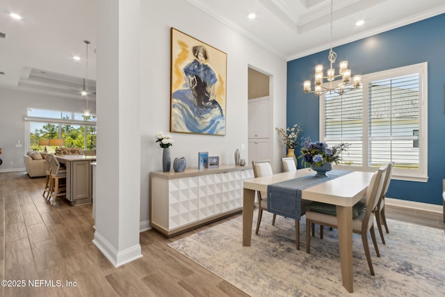 dining room featuring baseboards, a chandelier, wood finished floors, and a raised ceiling