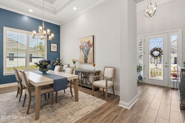 dining space featuring baseboards, a notable chandelier, ornamental molding, and a towering ceiling