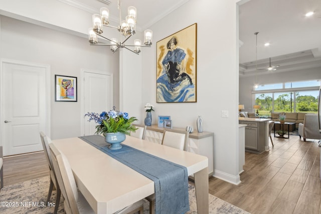 dining area with light wood-style floors, recessed lighting, baseboards, a tray ceiling, and ornamental molding