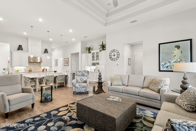 living room featuring a ceiling fan, visible vents, crown molding, light wood-type flooring, and recessed lighting