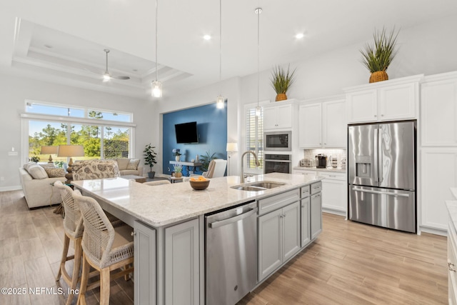 kitchen with ceiling fan, appliances with stainless steel finishes, a sink, open floor plan, and backsplash
