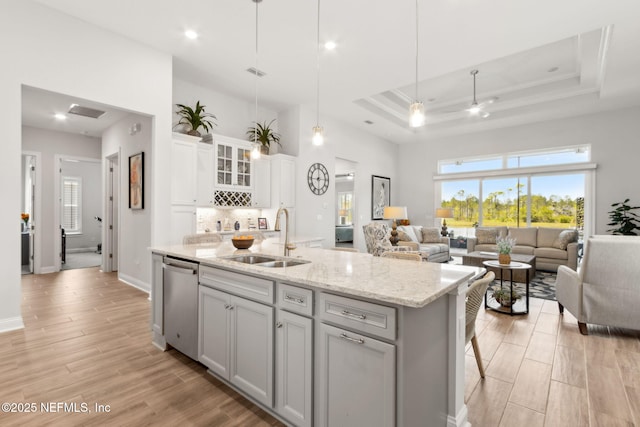 kitchen with a sink, stainless steel dishwasher, open floor plan, and an island with sink