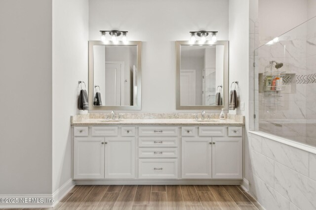 full bathroom with double vanity, a sink, and tiled shower
