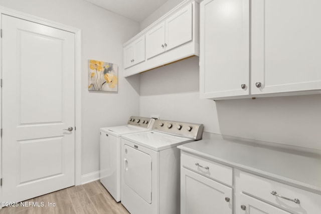 washroom featuring light wood-type flooring, washer and clothes dryer, cabinet space, and baseboards