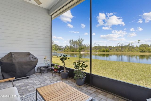 unfurnished sunroom with a healthy amount of sunlight, a water view, and a ceiling fan