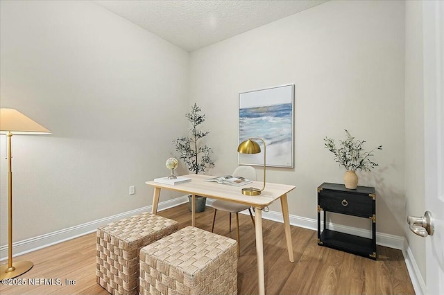 office area featuring light wood-style floors, baseboards, and a textured ceiling