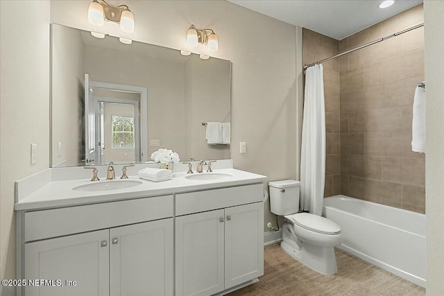 bathroom featuring double vanity, a sink, toilet, and wood finished floors