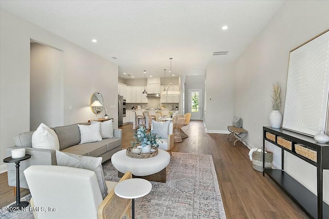 living room with visible vents, baseboards, recessed lighting, and dark wood finished floors