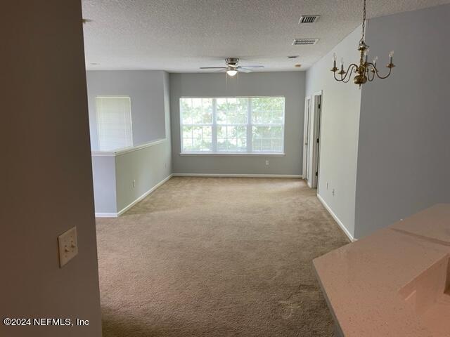12301 Kernan Forest Blvd Unit 302, Jacksonville, FL 32225 - unfurnished room featuring visible vents, carpet flooring, a textured ceiling, and ceiling fan with notable chandelier