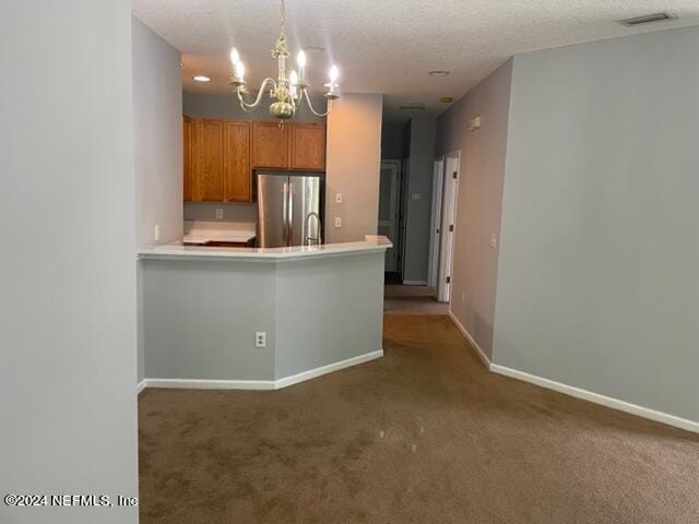 12301 Kernan Forest Blvd Unit 302, Jacksonville, FL 32225 - kitchen with brown cabinetry, light countertops, freestanding refrigerator, a chandelier, and carpet flooring