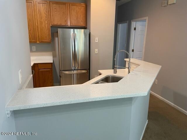 12301 Kernan Forest Blvd Unit 302, Jacksonville, FL 32225 - kitchen with a sink, baseboards, freestanding refrigerator, and brown cabinets