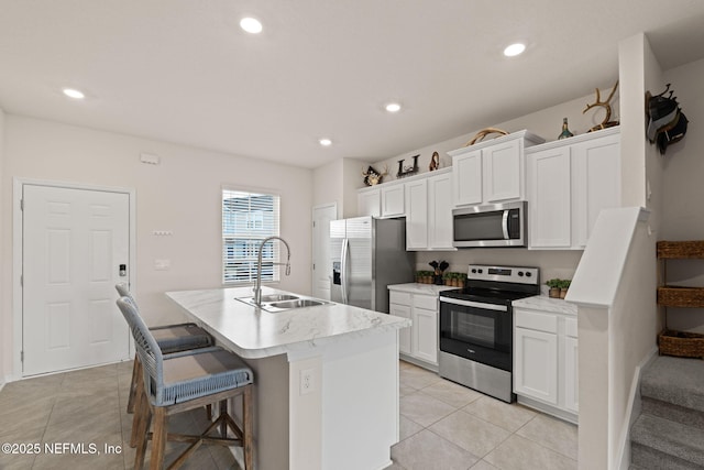3937 Oak Mill Rd, Orange Park, FL 32065 - kitchen with an island with sink, white cabinetry, appliances with stainless steel finishes, light tile patterned flooring, and a sink
