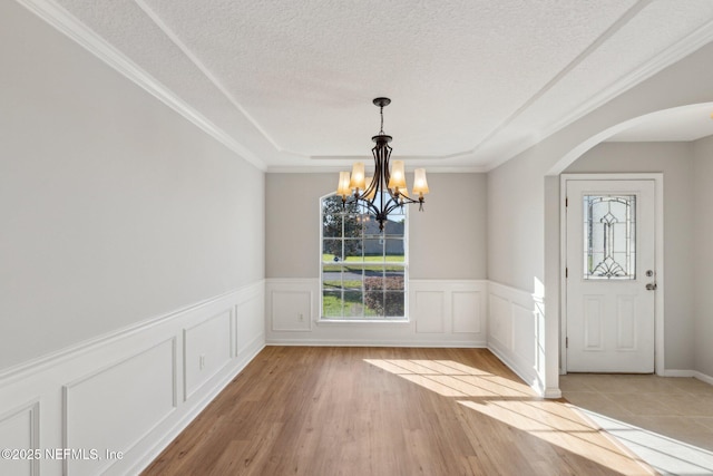 2423 Royal Pointe Dr, Green Cove Springs, FL 32043 - unfurnished dining area featuring a chandelier, arched walkways, light wood-type flooring, and a wainscoted wall