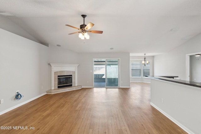 2423 Royal Pointe Dr, Green Cove Springs, FL 32043 - unfurnished living room featuring a tiled fireplace, vaulted ceiling, and light wood-style floors