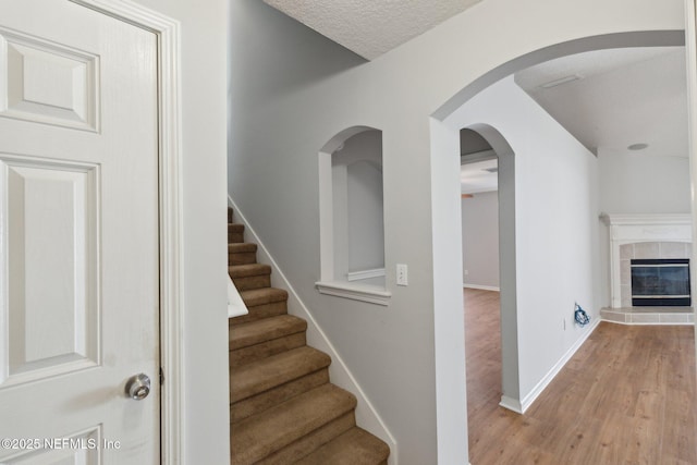 2423 Royal Pointe Dr, Green Cove Springs, FL 32043 - staircase featuring a tiled fireplace, baseboards, and wood finished floors
