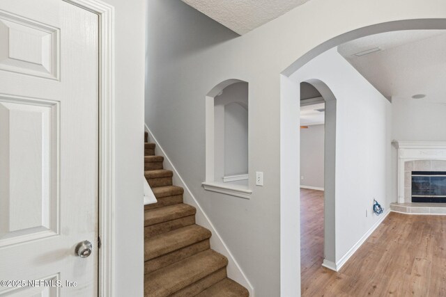 2423 Royal Pointe Dr, Green Cove Springs, FL 32043 - staircase featuring baseboards, a tile fireplace, and wood finished floors