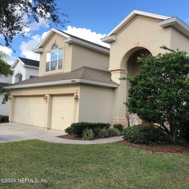 view of front of home featuring an attached garage, concrete driveway, a front yard, and stucco siding