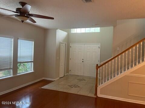 foyer entrance featuring baseboards, wood finished floors, ceiling fan, and stairs