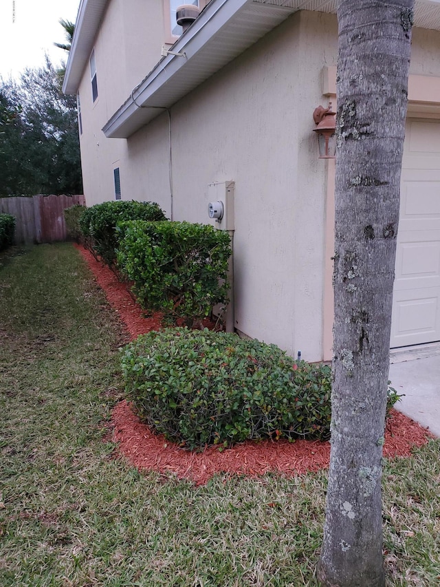 view of side of property with stucco siding, fence, and a garage