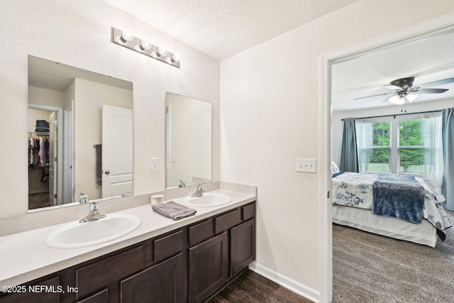 ensuite bathroom with a sink, ceiling fan, double vanity, and connected bathroom