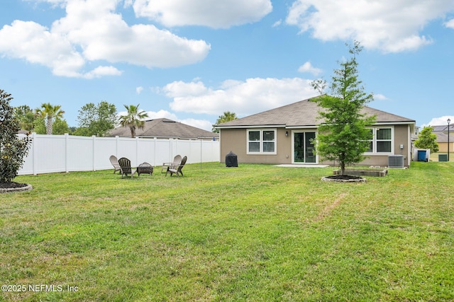 view of yard with a fenced backyard, an outdoor fire pit, and central AC unit