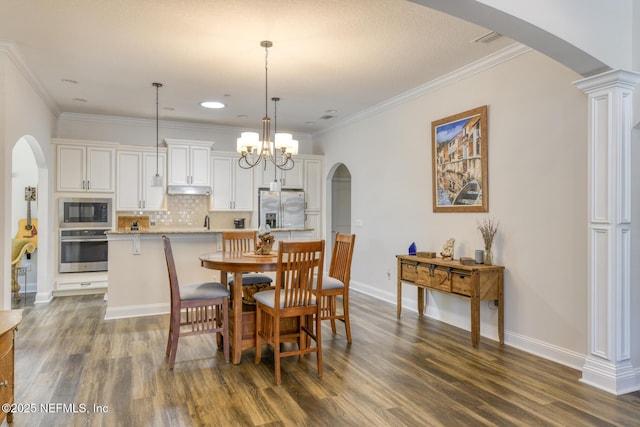 86 Amacano Ln, Saint Augustine, FL 32084 - dining area featuring arched walkways, dark wood-style floors, baseboards, and crown molding
