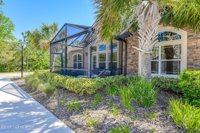 86 Amacano Ln, Saint Augustine, FL 32084 - view of property exterior with stucco siding, stone siding, and glass enclosure