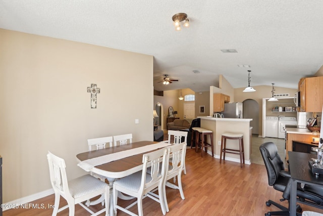 3620 Braeden Ct, Middleburg, FL 32068 - dining room featuring arched walkways, washer and dryer, light wood-style flooring, and vaulted ceiling