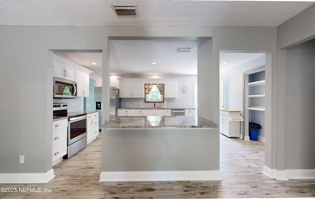 4147 Saunders Dr, Middleburg, FL 32068 - kitchen with light wood finished floors, a textured ceiling, appliances with stainless steel finishes, and white cabinetry