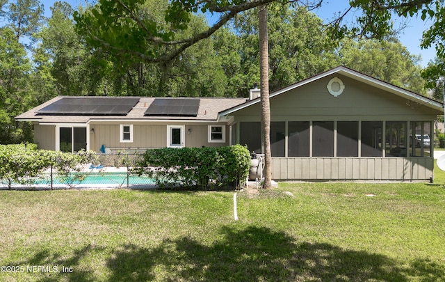 4147 Saunders Dr, Middleburg, FL 32068 - back of house featuring roof mounted solar panels, a lawn, a chimney, and a sunroom