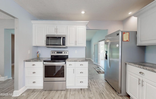 4147 Saunders Dr, Middleburg, FL 32068 - kitchen featuring white cabinets, light wood-type flooring, baseboards, a textured ceiling, and appliances with stainless steel finishes