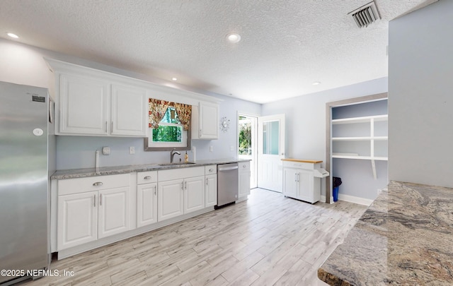 4147 Saunders Dr, Middleburg, FL 32068 - kitchen featuring stainless steel appliances, visible vents, a sink, light wood-style flooring, and a textured ceiling