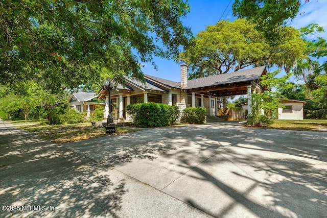 4215 Irvington Ave, Jacksonville, FL 32210 - view of front facade featuring a chimney, stone siding, an attached carport, and concrete driveway