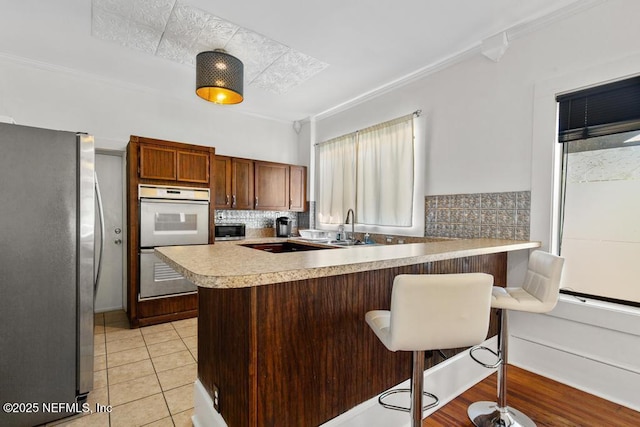 4215 Irvington Ave, Jacksonville, FL 32210 - kitchen featuring freestanding refrigerator, double oven, a peninsula, light countertops, and a sink