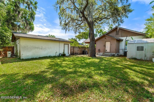 4215 Irvington Ave, Jacksonville, FL 32210 - rear view of house with an outdoor structure, concrete block siding, fence, a lawn, and a storage unit