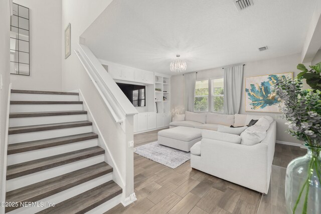 190 Palisade Dr, Saint Augustine, FL 32092 - living room with a notable chandelier, stairway, visible vents, and wood finished floors