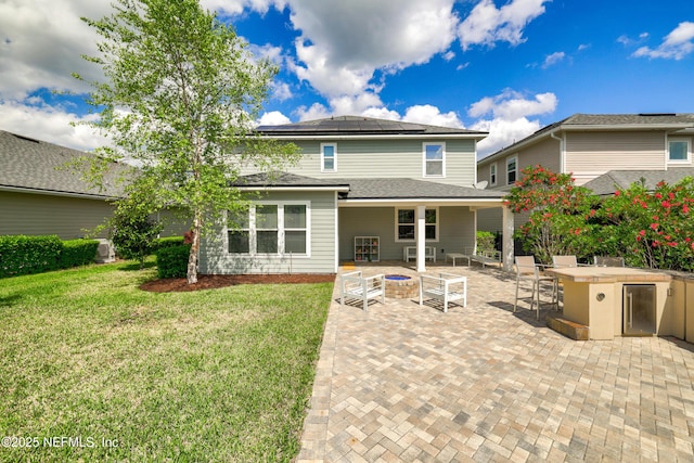 190 Palisade Dr, Saint Augustine, FL 32092 - rear view of property featuring roof mounted solar panels, outdoor dry bar, a patio area, a lawn, and an outdoor fire pit