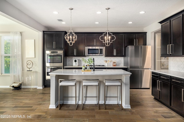 190 Palisade Dr, Saint Augustine, FL 32092 - kitchen with dark wood finished floors, stainless steel appliances, an inviting chandelier, visible vents, and a kitchen bar
